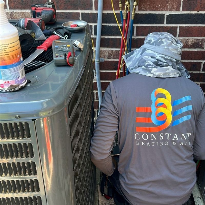 Constant technician servicing an outdoor AC condenser